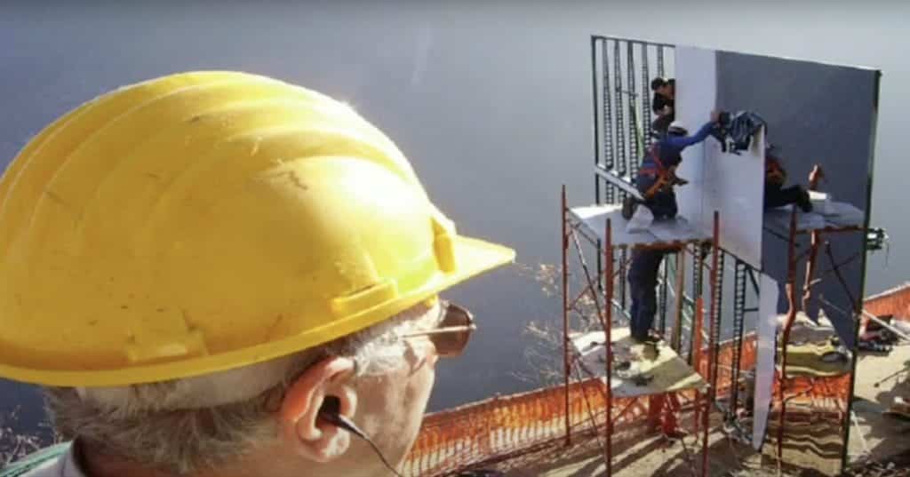 A man in a construction hat overseeing the construction of the giant mirror for Viganella's sunlight. 